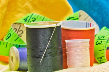 Sewing item tools isolated on colored clothing with macro details including spools of thread,...