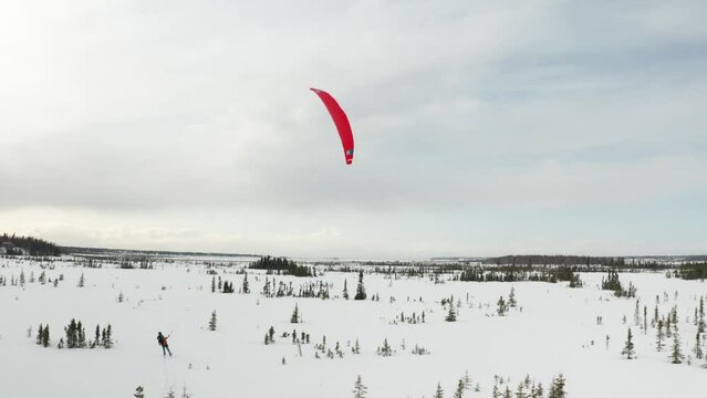 Drone footage of a skier para-skiing with a parachute on a windy winter day in Kenai, Alaska.