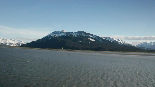 Drone footage of a water skier para-skiing with a parachute on a windy summer day in Turnagain Arm of the Cook Inlet in Alaska.