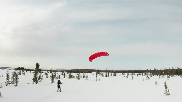 Drone footage of a skier para-skiing with a parachute on a windy winter day in Kenai, Alaska.
