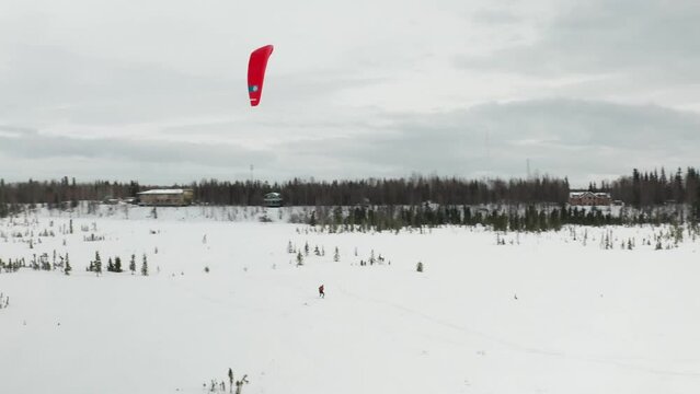Drone footage of a skier para-skiing with a parachute on a windy winter day in Kenai, Alaska.