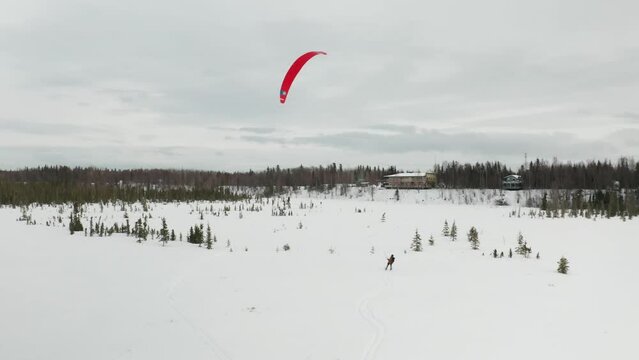 Drone footage of a skier para-skiing with a parachute on a windy winter day in Kenai, Alaska.
