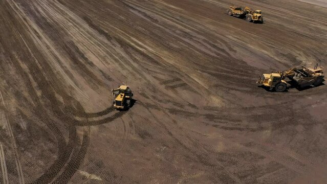 Motor scrapers and sheepsfoot tractor on job site grading the land for construction.