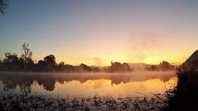 Time lapse of lake fog steaming off the surface of the water at sunrise