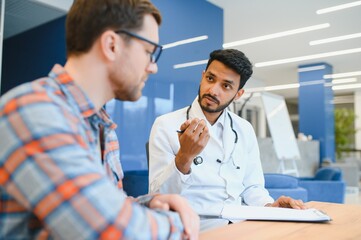 medicine, healthcare and people concept - indian doctor young male patient meeting at hospital