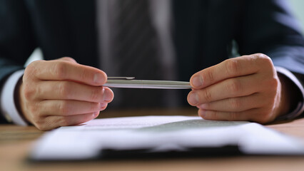 Businessman in suit holding metal ballpoint pen before signing contract closeup. Partnership in business concept