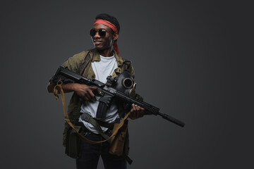 Shot of cheerful pirate of african ethnic with rifle in setting of post apocalypse.