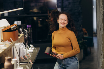 Fototapeta na wymiar A woman buys a hair dryer in an electronics store