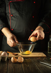 Cooking a delicious omelet for breakfast from eggs by the chef's hands. Work environment on the kitchen table. Egg in the cook hand