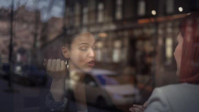 Friendly young confident female colleagues having a pleasant chat at coffee shop during work break, talkative coworker discussing new project