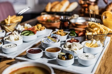 View of sauces, vegetables and fries on white plate