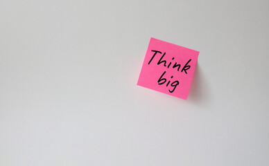 Think big symbol. Pink steaky note with words Think big. Beautiful white background. Business and Think big concept. Copy space.