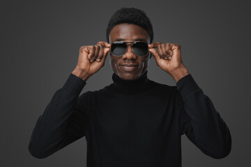 Obraz premium Shot of isolatedon grey background african man holding his sunglasses.