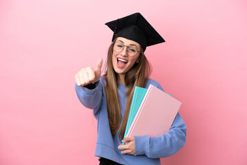 Young student woman wearing a graduate hat isolated on pink background with thumbs up because something good has happened