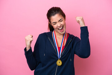 Young Brazilian sport woman with medals isolated on pink background celebrating a victory