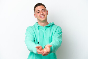 Young brazilian man isolated on white background holding copyspace imaginary on the palm to insert...