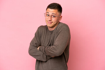 Young Brazilian man isolated on pink background making doubts gesture while lifting the shoulders