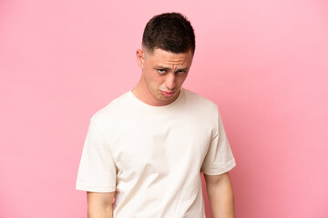 Young Brazilian man isolated on pink background with sad expression