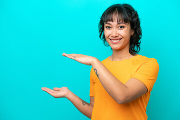 Young Argentinian woman isolated on blue background holding copyspace to insert an ad