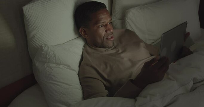 African American Businessman Working on a Digital tablet in Bed at Nighttime