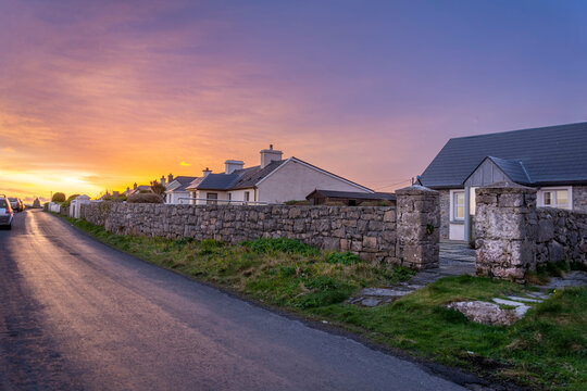 Sunrise at the end of the road with old irish cottages and stone walls on Inishmore island