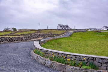 Cloudy landscape with an old Irish cottage and stonewall in spring