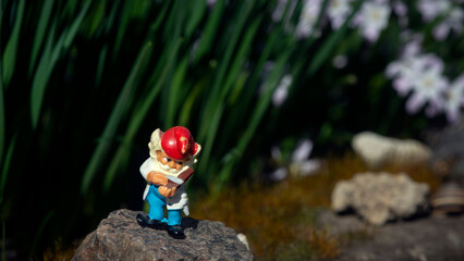 Gnome figurine in the garden.Flower bed with fairy-tale characters.Bright locations with fabulous...