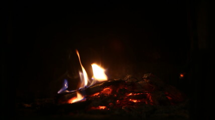 Close up the lash of flames, fire, hot coals on a dark background