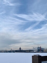 View from Mytninskaya embankment to the ice-covered Neva, Spit of Vasilevsky Island, Rostral columns and St. Isaac's Cathedral. Against the background of the sky with beautiful clouds in St. Petersbur