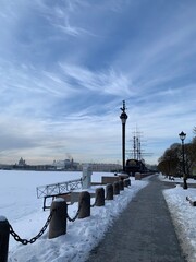View of the Mytninskaya embankment, the column and the ship Flying Dutchman. Against the background of a blue sky with clouds in St. Petersburg.