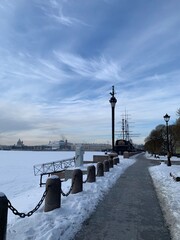 View of the Mytninskaya embankment, the column and the ship Flying Dutchman. Against the background of a blue sky with clouds in St. Petersburg.