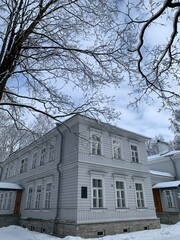 A gray two-story building among snow-covered trees in a city park on Elagin Island in St. Petersburg.
