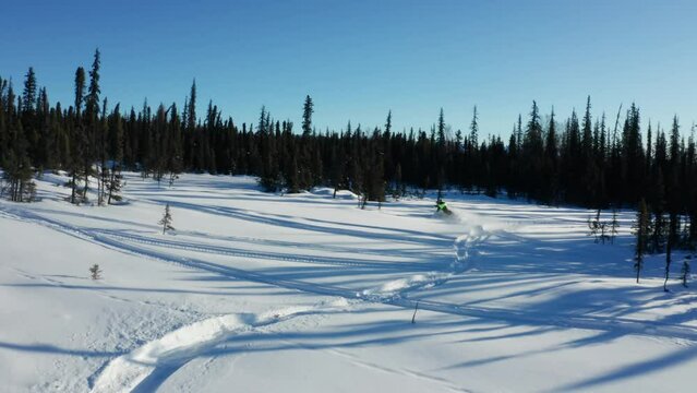 Two friends snowmobiling through the snow-covered terrain of Talkeetna, Alaska, pushing the limits of their snowmobiles, having fun and enjoying the breathtaking winter landscape