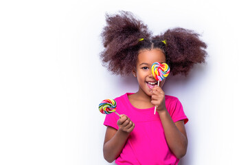 Girl afro, lollipops. Smile little african american girl eating lollipop, holding pink sweet colorful lollipop candy, sweets. Cute multiracial small girl smiling lollipop in hand on background