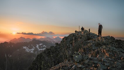 People at the edge of a rocky mountains at a mesmerizing sunset