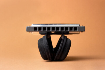 A professional harmonica lies on an open black case, with holes in the frame.  On a light brown...