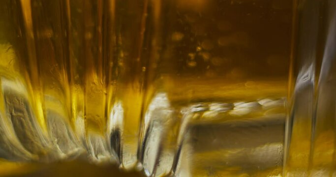 Macro close up of ice dropping into sctoch in fancy glass and bring stirred with barspoon
