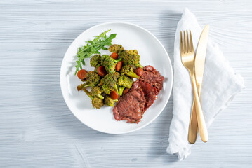 Breakfast in a white plate of broccoli vegetables, herbs and ham slices