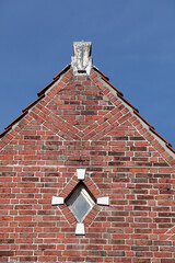 Rautenförmiges Fenster und Dachgiebel an einer rötlichen Hauswand, Bremen, Deutschland