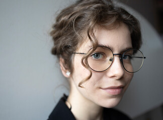face portrait confident teenage girl 18 years old, schoolgirl, college student looking at camera. young smart woman with glasses. Selective focus, copy space