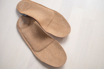 orthopedic insoles for shoes brown, made of natural materials, lies on a light surface of the table. Prevention and treatment of flat feet, shoe accessories