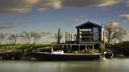 Cabane de pêche sur pilotis avec un voilier, paysage typique de la Charente-Maritime le long de...