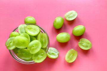 Green grapes in a glass plate, pink background