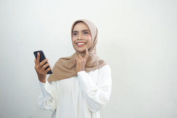 Fototapeta premium Excited beautiful Asian muslim woman showing mobile phone isolated over white background