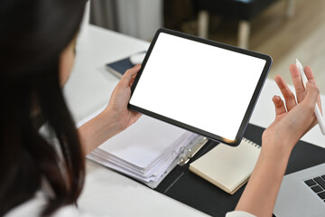View over shoulder of businesswoman hands holding digital tablet. White screen for graphic display montage