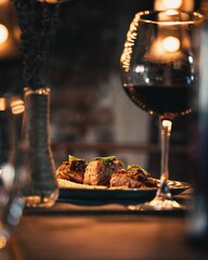 Selective focus of grilled salmon served with a glass of red wine and a flower vase on the table