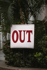 Closeup shot of a sign showing to keep out of the area, with trees and shrubs in the background