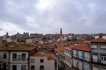 Fototapeta na wymiar Panorámica de la ciudad de Oporto con los tejados rojos y las fachadas de colores bajo un cielo nublado.