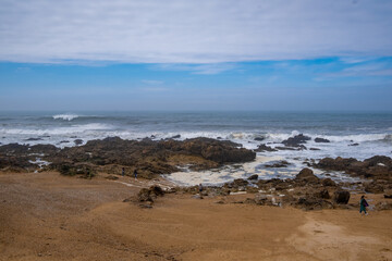 Fototapeta na wymiar Una de las playas de Matosinhos, en Oporto, con el océano Atlántico revuelto al fondo bajo un cielo nublado.