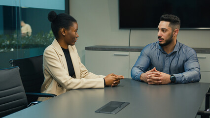 Indian Arabian man CEO businessman recruiter employer talking in office with African American woman female worker customer candidate for job interview consultation business meeting diverse colleagues